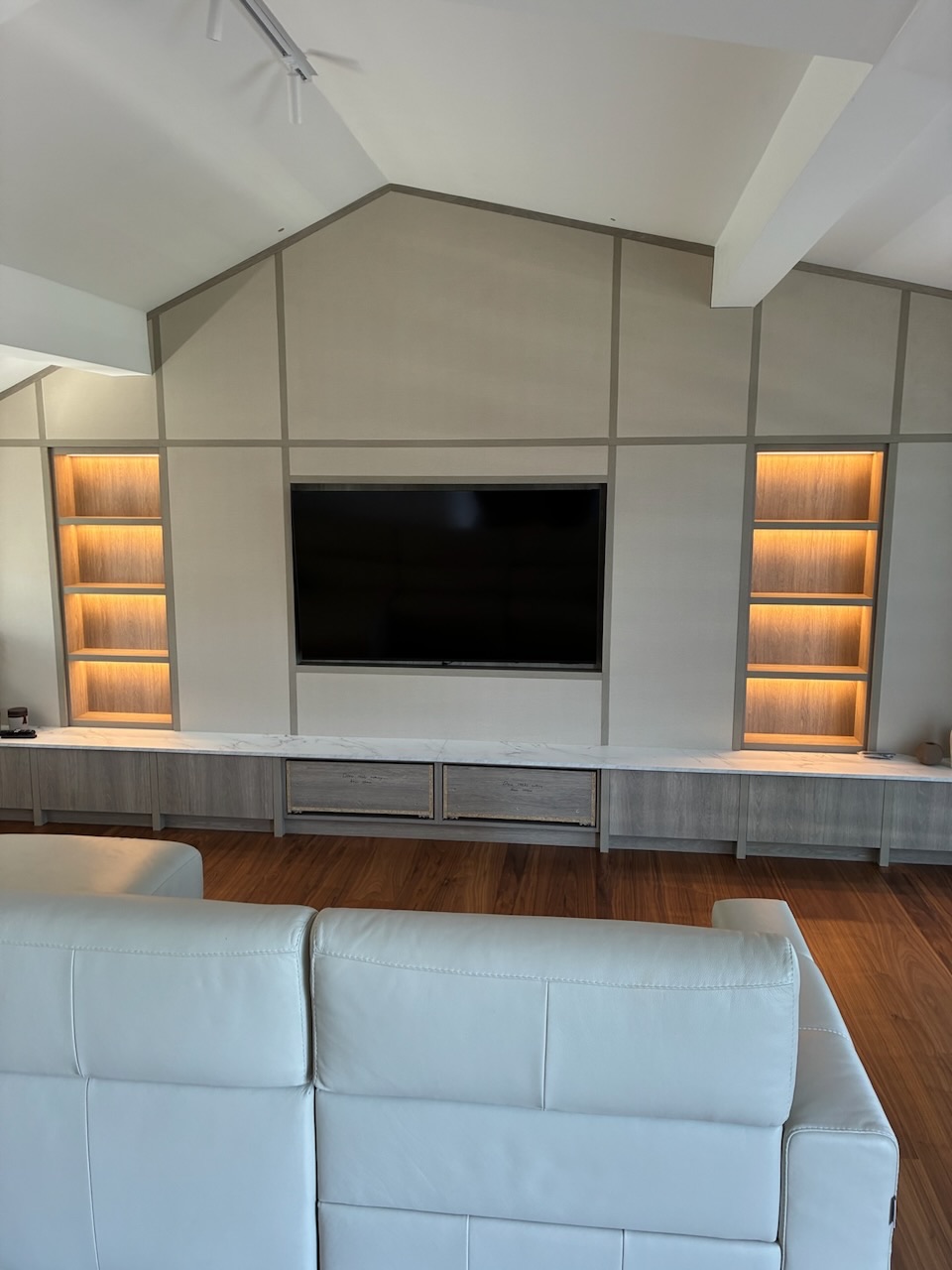 Barn conversion main hall — bespoke TV wall with LED-lit oak shelving under vaulted ceiling, Westby, Lytham — Wilsons Systems