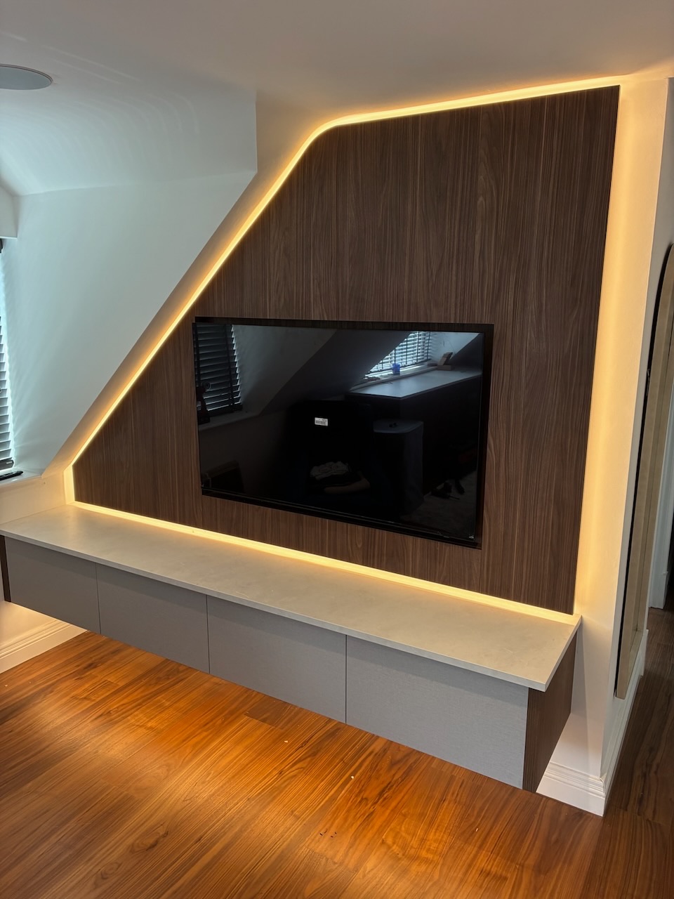 Bedroom with bespoke angled walnut joinery panel following the roofline, integrated TV and LED backlighting, Westby, Lytham — Wilsons Systems